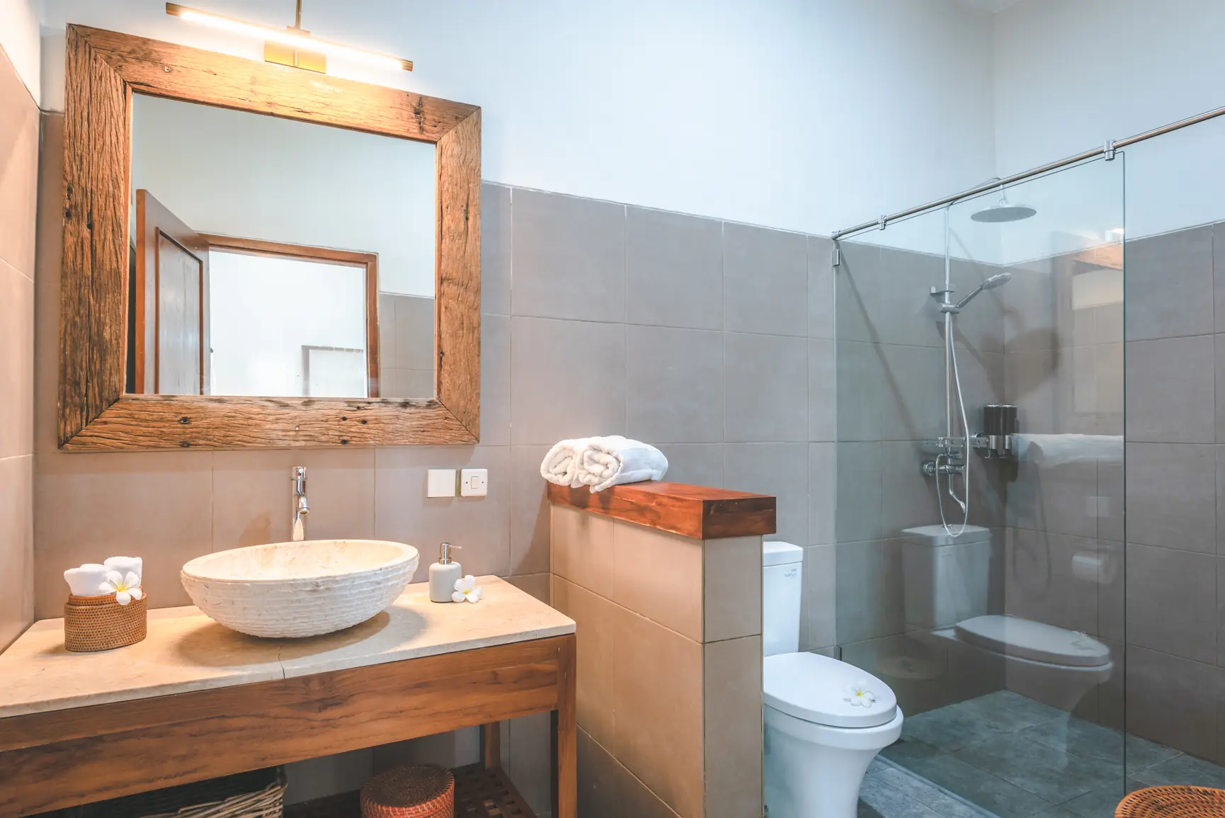 Garden bedroom bathroom with stone vessel sink, wooden-framed mirror, and walk-in shower