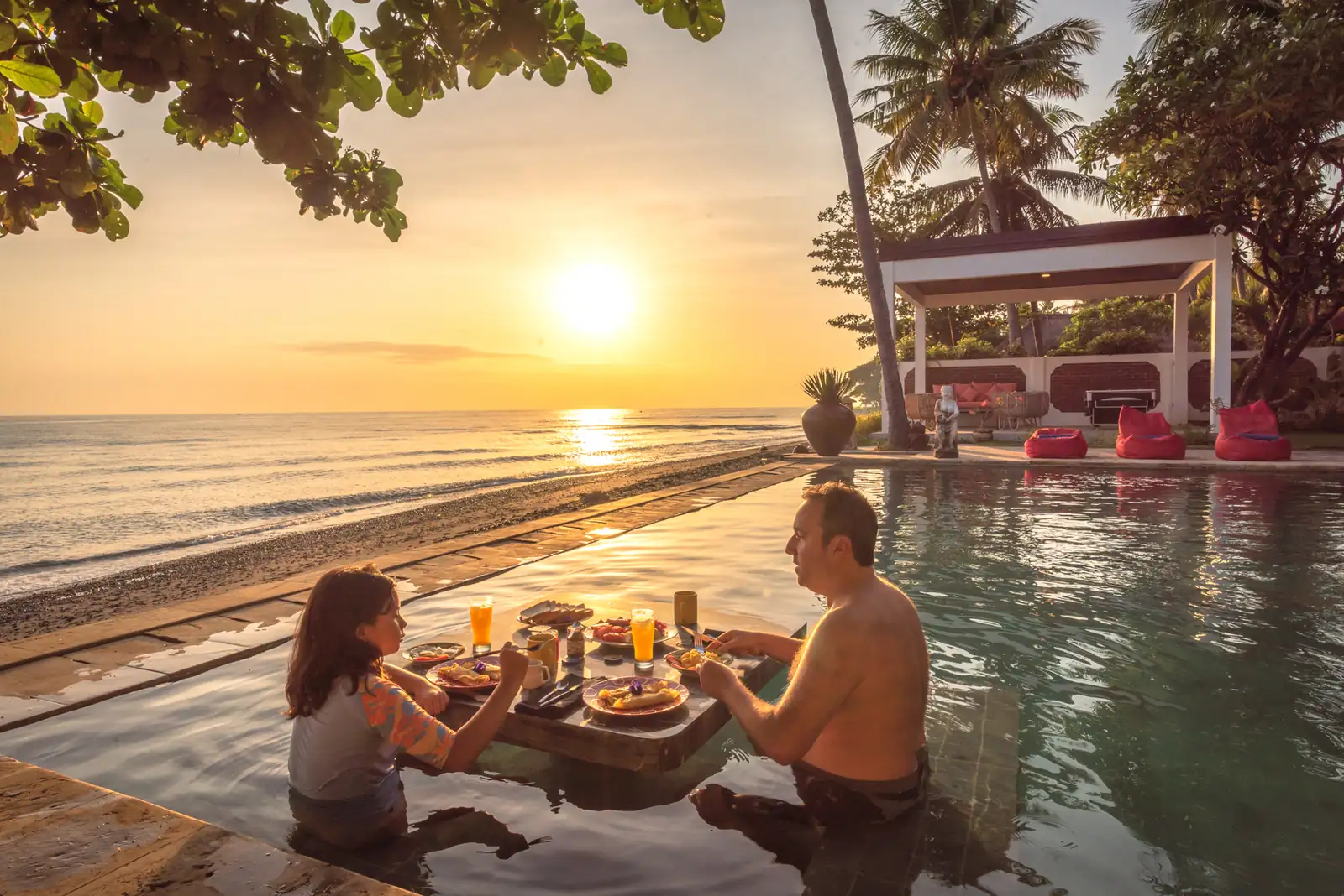 Breakfast served on a teakwood table half-submerged in the infinity pool at sunrise, Primavera Beach House.