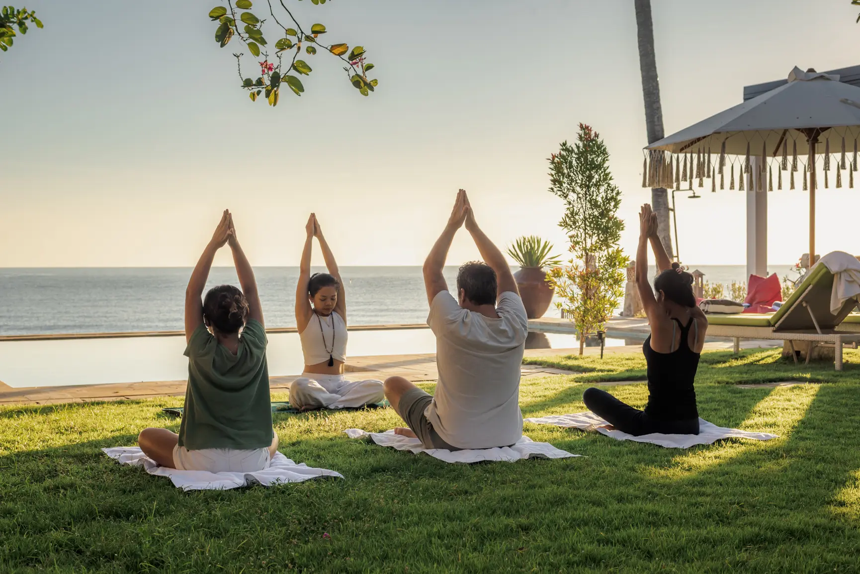A group practising yoga on the lawn facing the sea at Primavera Beach House.